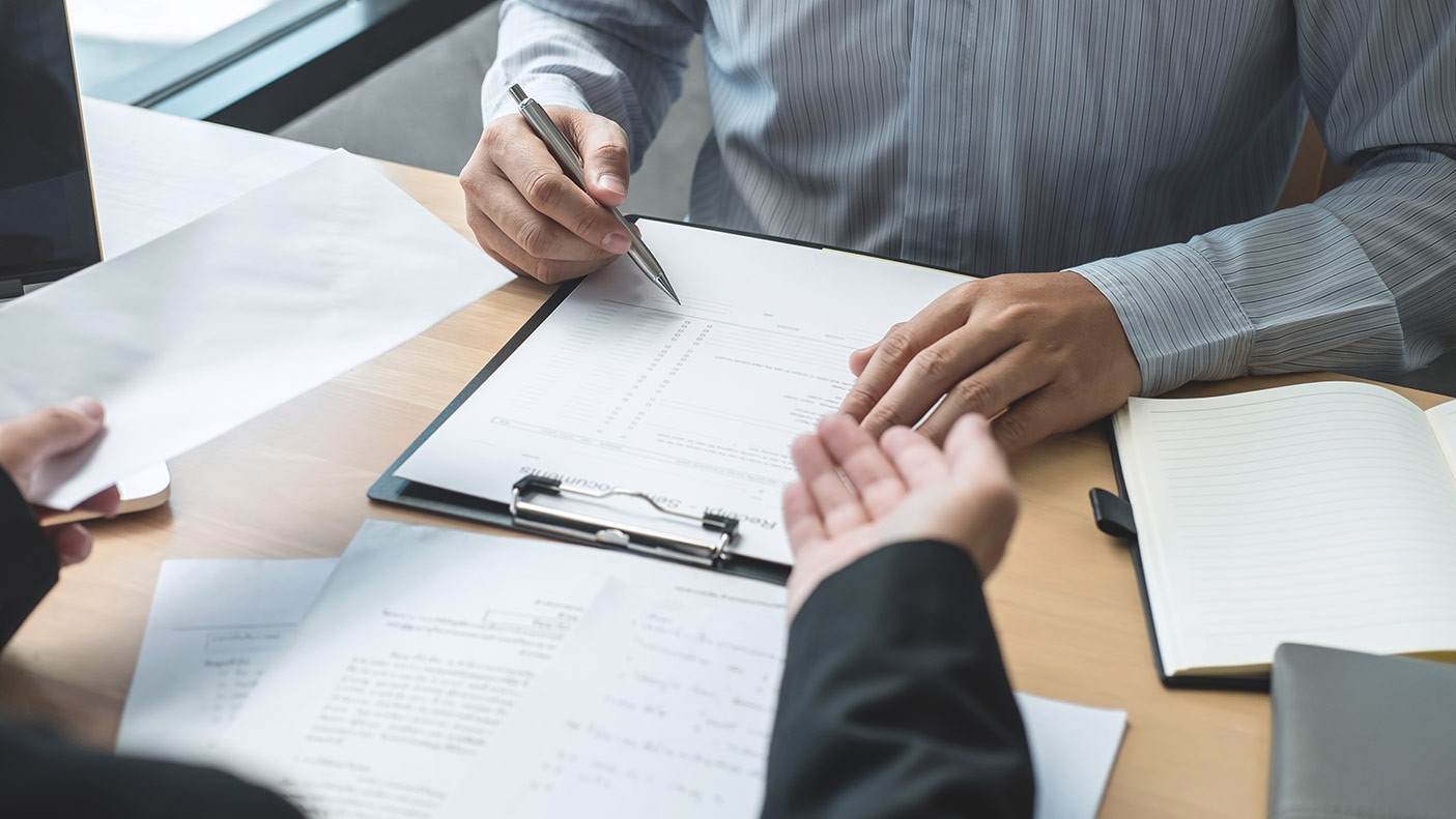 Close up of 2 office workers checking a page on a clipboard