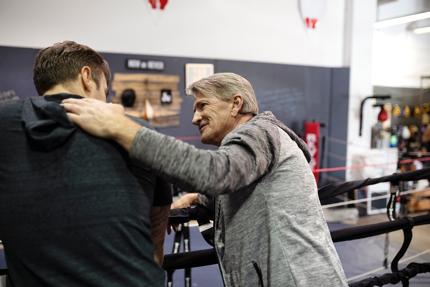 Trainer and male boxer talking in gym - stock photo